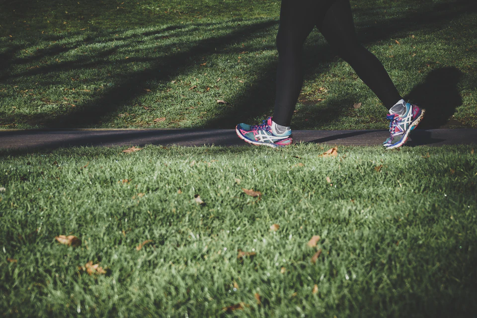 A runner in trainers on a grassy park path in London