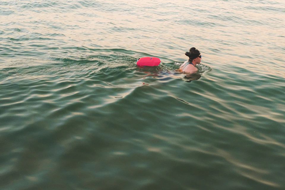 An open water swimmer towing a bright pink tow float