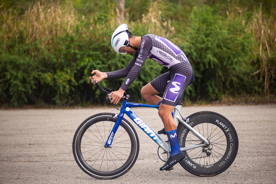 A cyclist in a white helmet on a blue time trial bike